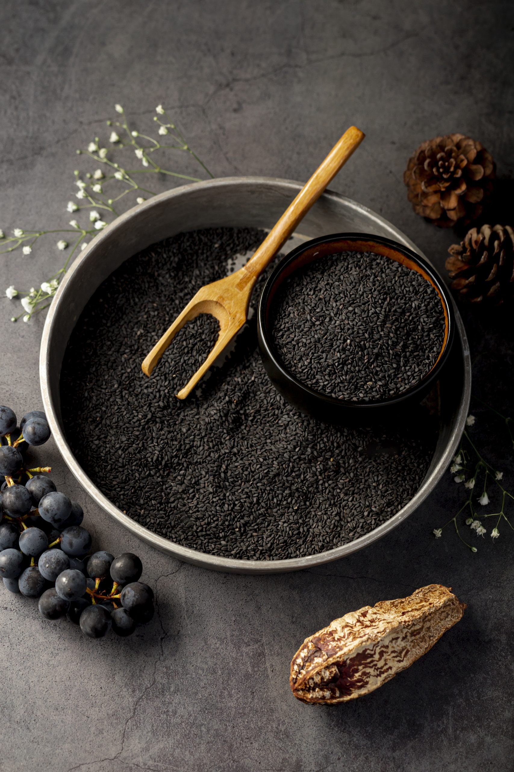 grey metallic plate filled with poppy seeds grapes grey background